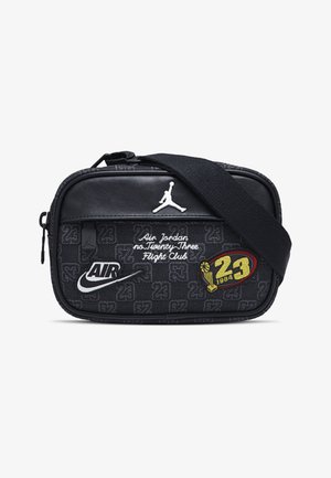 Juodas audinio pečių krepšys su lygia odine priekiu, baltu Jordan logotipu, siuvinėtomis aplikacijomis ir ryškiu „23“ dizainu. Kompaktiška stačiakampio forma.