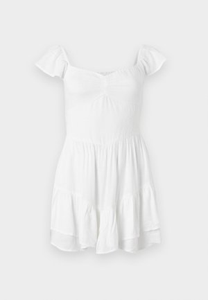 Balta plati suknelė su trumpomis pūstomis rankovėmis, tekstūruota medžiaga, susiraukšlėta liemeniu ir voluminous apvadu, turinti paprastą, klasiką atitinkančią dizainą.