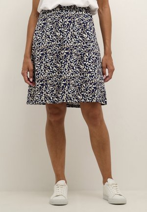 Granatowa spódnica w liściasty wzór w kolorze kremowym i beżowym, z elastycznym pasem i luźnym krojem, zestawiona z białymi tenisówkami.