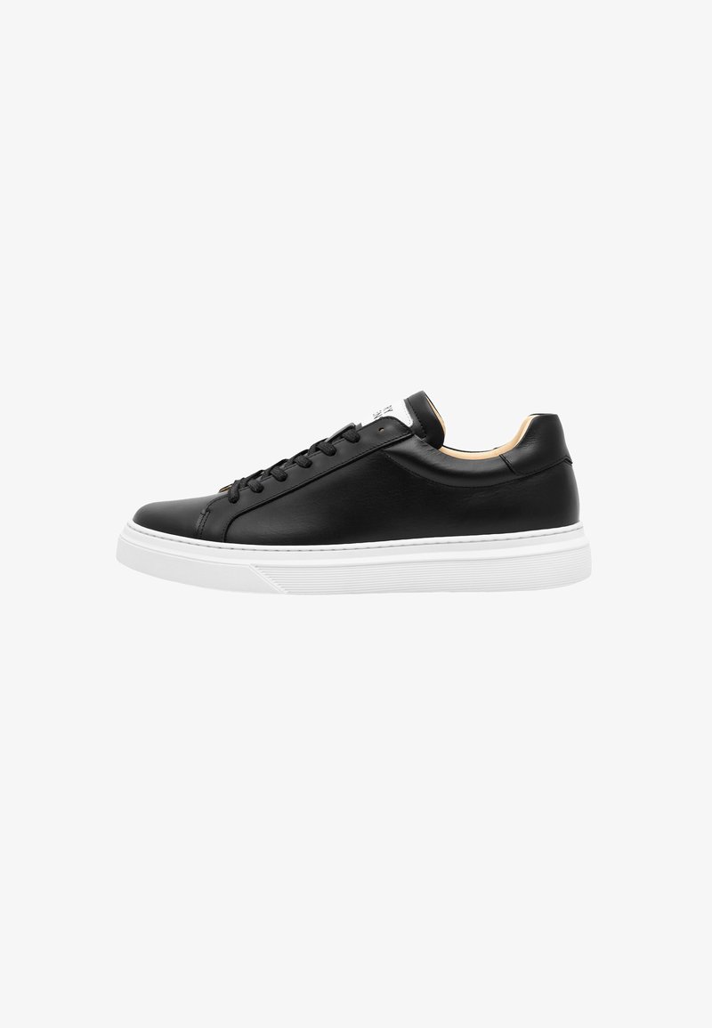 Schwarze Leder sneakers mit flachen Schnürsenkeln, weißer Sohle und minimalistischem Design; ausgestattet mit einem kontrastierenden beigen Innenfutter und subtiler Markenkennzeichnung auf der Zunge.