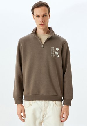 Sudadera con cremallera en color marrón, hecha de una mezcla de algodón, que cuenta con un diseño geométrico en blanco en el lado izquierdo del pecho y puños y dobladillo acanalados.