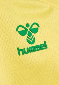 Gul texturerad tyg med en grön logotyp som har ett bi-motiv och ordet "hummel" i fet, modern typografi under.