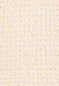 Gros plan d’un tissu tricoté doux et duveteux avec une base blanc crème et de subtiles taches orange et jaunes.