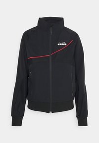 Svart zip-jacka med hög krage, med röd accentlinje över bröstet och logotyp på övre vänstra sidan. Tillverkad av ett mjukt tyg.