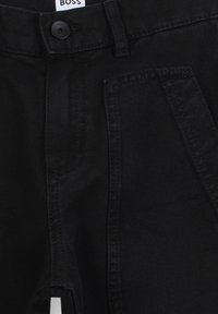 Pantaloni in denim neri con taglio dritto, dettagli di cucitura sottili e design della tasca frontale. Chiusura con bottone in vita con logo.