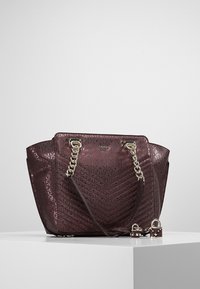 Bolso burdeos oscuro con patrón en relieve, asas de cadena plateadas y un candado decorativo. Exhibido sobre una superficie de color claro.