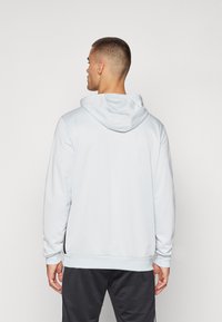 Helle blaue Kapuzenjacke mit Kordelzugkapuze, langen Ärmeln und gerippten Bündchen. Der Stoff wirkt glatt und hat eine lockere Passform.