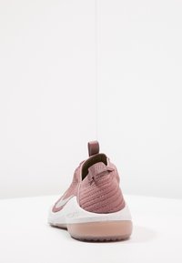 Pink textured fabric shoe with a curved silhouette, white midsole, and transparent rubber outsole. Features a pull tab at the heel.