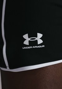 Μαύρο αθλητικό σορτς με λευκή επένδυση και το λογότυπο Under Armour τοποθετημένο πάνω από το εκτεθειμένο μηρό.