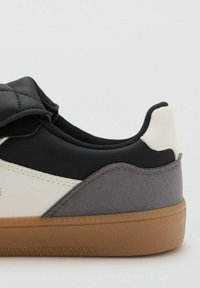 Sneaker in pelle nera con pannello laterale bianco e dettagli in suede grigio. Caratterizzata da una suola in gomma e un colletto imbottito per il comfort.