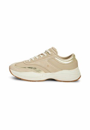 Baskets basses beige et dorées avec lacets blancs, semelle blanche épaisse et détails texturés subtils sur le côté et le talon.