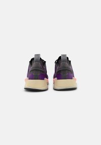 Lila och svarta träningsskor med strukturmesh-övre, genomskinligt hälstöd och ljusgummisula. Förstärkta dragöglor.