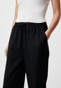 Pantaloni jogger neri realizzati in morbido tessuto, con vita elasticizzata e coulisse. Presentano tasche laterali e una vestibilità comoda.