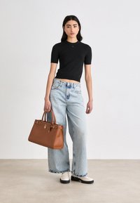Svart tettsittende kortermet topp, lyse vaskede brede jeanstype med frynset kanter, og en brun strukturert håndveske med detaljert gullhardware.
