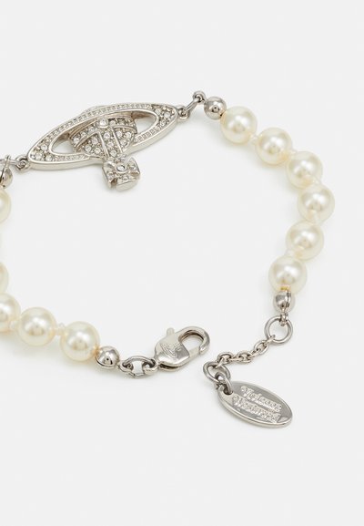 Pulsera de perlas blancas con un cierre en tono plateado decorado con acentos de cristal y una pequeña etiqueta grabada.