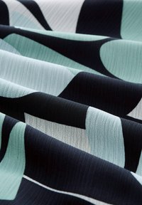 Musterstoff in Schwarz, Hellblau und Weiß. Die Textur wirkt glatt mit dezenten horizontalen Linien.