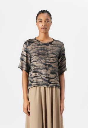 Korte ermer, ribbet topp i beige og svart tigermønstret design, med rund halslinning og avslappet passform. Kombinert med en flytende beige skjørt.