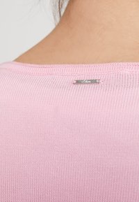 Haut en maille rose pâle avec un col rond et une petite étiquette argentée « s.Oliver » à l'arrière, présentant une texture lisse.