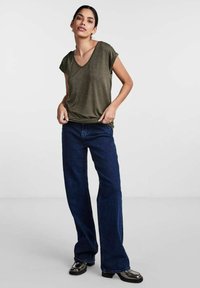 Olive green short-sleeve V-neck top paired with wide-leg dark blue denim jeans and shiny black shoes, with relaxed, casual fit.