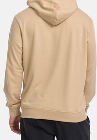 Sweat à capuche beige avec une texture douce, une capuche à cordon ajustable et des poignets et une ceinture côtelés. Présente une coupe décontractée, vue de dos.