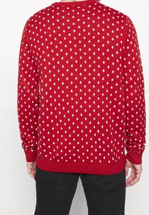 Roter Strickpullover mit einem weißen und blauen Rautenmuster, mit gerippten Bündchen und Saum. Die Rückansicht zeigt die vollständige Musterabdeckung.