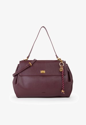 Bordeaux læder håndtaske med dobbelte stropper, guldtonet spænde og dekoreret nøglering med flettråd og rund træ charm.