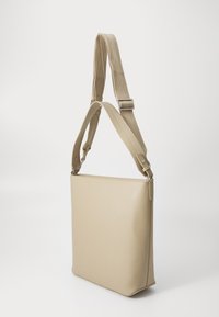 Borsa a spalla in pelle beige con una texture liscia, forma rettangolare e tracolla regolabile. Design minimalista senza dettagli hardware visibili.