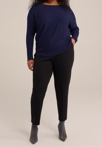 Námořnická žebrovaná dlouhá halenka, spárovaná s černými kalhotami na míru a šedými kotníkovými botami. Halenka má uvolněný střih a zakřivený lem.