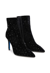 Stivali alla caviglia in velluto nero con punta a punta, alti tacchi a stiletto e decorazioni in strass neri, dotati di cerniere laterali.