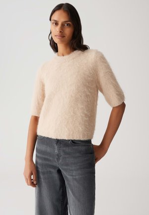 Pudrig rosa, flauschiger Kurzarmpullover mit Rundhalsausschnitt, kombiniert mit dunkelgrauen, weit geschnittenen Jeans aus einem weichen, strukturierten Stoff.