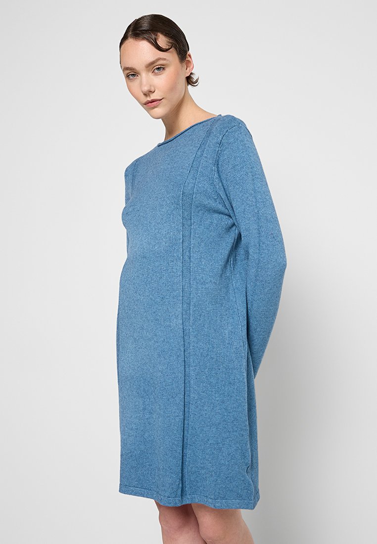 Robe bleue à manches longues en textile doux. Elle présente une coupe décontractée, un col bateau et des détails sur les panneaux latéraux. Design simple et sans embellissements.