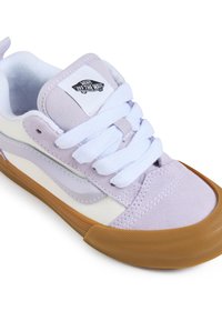 Scarpe Vans con tomaia in suede lilla, linguetta in rete bianca, stringhe bianche e suola in gomma. Presenta il logo sulla linguetta e un design a strisce laterali.
