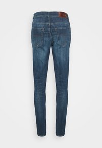 Smal passform blå denimjeans med en lätt blekning. Bakdelen har två påsydda fickor och en läderdetalj i midjan. Klassisk femfickorsdesign.