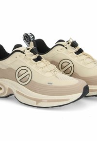 Beige sneakers met een textiel bovenwerk, zwarte accenten, een ronde logo aan de zijkant en een dikke, gevoerde zool.