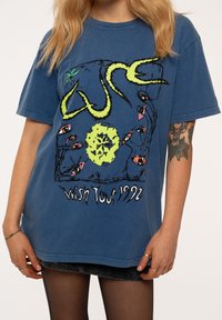 Blue cotton t-shirt with a loose fit, featuring a graphic design of eyes and a yellow snake, text “Wish Tour 1992” in a distressed style.