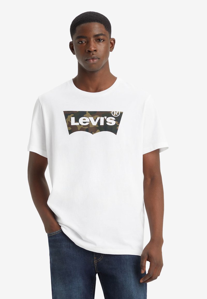 Weißes Baumwoll-T-Shirt mit einem Tarnmuster-Logo von Levi's auf der Vorderseite. Kurze Ärmel und Rundhals-Design. Kombiniert mit dunkelblauen Denim-Jeans.