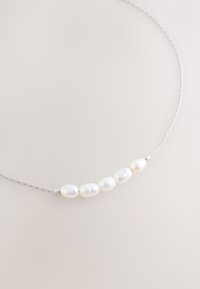 Sterling silver necklace featuring five oval-shaped white pearls, evenly spaced along a delicate twisted chain.