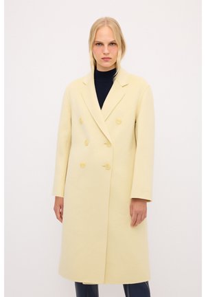 Cappotto giallo doppiopetto con un design strutturato, colletto a rever e dettagli con bottoni, realizzato in un morbido tessuto testurizzato.