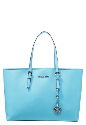 Sac fourre-tout en cuir bleu clair avec deux bretelles et un pendentif rond argenté avec le logo MK suspendu à une des bretelles.