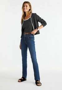 Mustriga must-valge lühike topp, millele on kombineeritud sinised kitsad teksad. Välimus on täiustatud mustade sandaalidega, millel on kuldne aktsent.