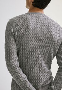 Pull gris en tricot présentant un motif torsadé texturé, un col rond et des poignets côtelés. La vue de dos met en valeur le design complexe.