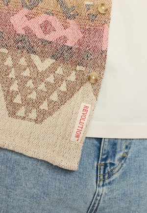 Multikleurige gebreide cardigan met een geometrisch patroon, beige basis, roze en bruine accenten, voorzien van drie knopen en een label gemarkeerd "REVOLUTION."