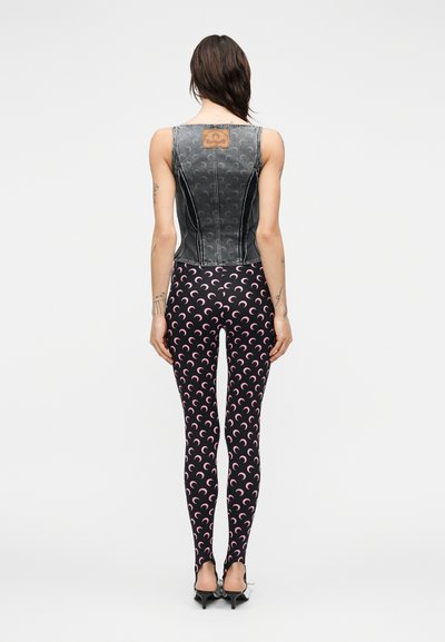 Αμάνικη τοπ από τζιν σε σκούρο γκρι με διακοσμητική ετικέτα και εφαρμοστά μαύρα κολάν με ροζ μοτίβο ημισελήνου.