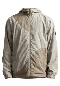Giacca leggera con cappuccio in beige e taupe, caratterizzata da un design geometrico, chiusura con zip e polsini regolabili. Realizzata in tessuto testurizzato.