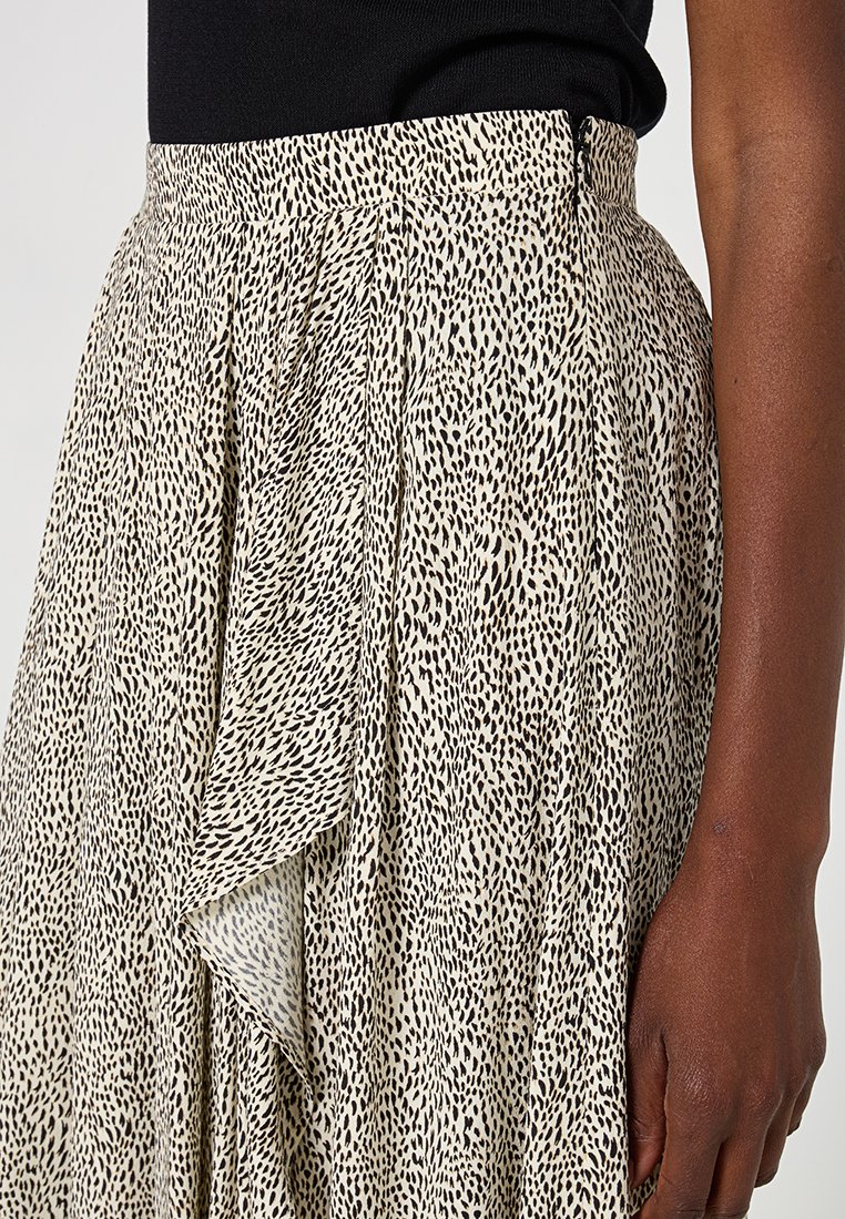 Beżowa spódnica z teksturowanej tkaniny w czarny nakrapiany wzór, z wysokim stanem i drapowanymi detalami po jednej stronie.