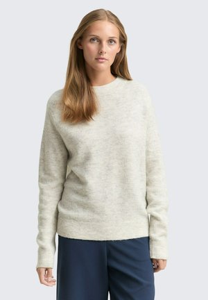 Hellgrauer Pullover aus weichem, strukturiertem Material, mit rundem Ausschnitt und langen Ärmeln, kombiniert mit dunkelblauen Hosen.