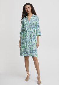 Rochie cămașă cu imprimeu floral albastru și verde, cu mâneci trei sferturi și o curea la talie. Material ușor și moale.