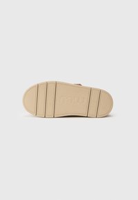 Suola di scarpa in gomma di un beige chiaro con grip testurizzato, caratterizzata da distinti solchi orizzontali e verticali. Logo del marchio impresso sulla superficie.