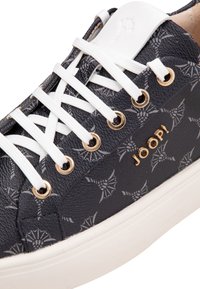 Zapatilla azul marino con un acabado texturizado, que presenta un sutil patrón de telaraña, cordones blancos, ojetes dorados y un logotipo en el lateral.