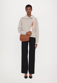 Beige ribbestrikket genser med stor krage, kombinert med svarte vide bukser. Brun crossbody-veske med flat design og metallisk stroppdetalj.